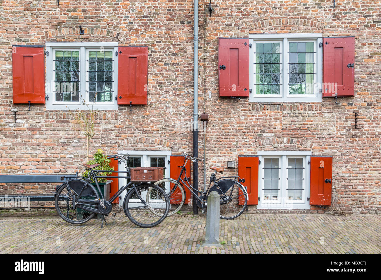 Vinate Black Dutch bikes in front of an old castle wall with windows and shutters Stock Photo