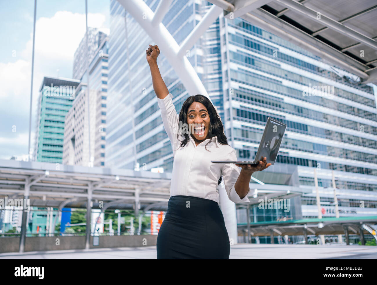 Cheerful African American business woman with arms raised in success ...