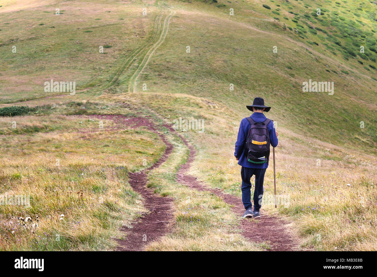 A young man with sombrero and walking stick hiking on the highlands of a  mountain Stock Photo - Alamy