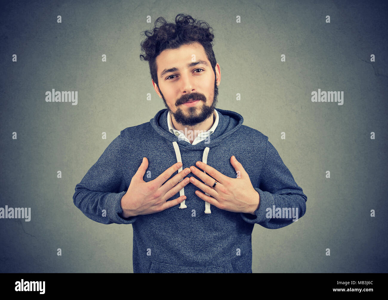 Faithful man keeps hands on chest near heart, shows kindness expresses sincere emotions, being kind hearted and honest. Stock Photo