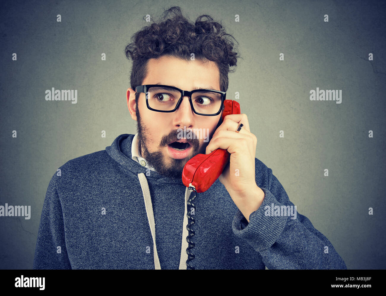 Stunned young man receiving unexpected news over the phone Stock Photo