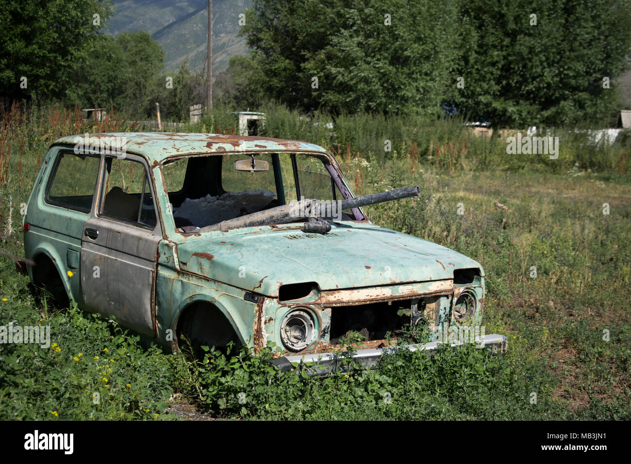 Old, abandoned, broken down car in a remote Kazakhstan village near Kolsai Stock Photo