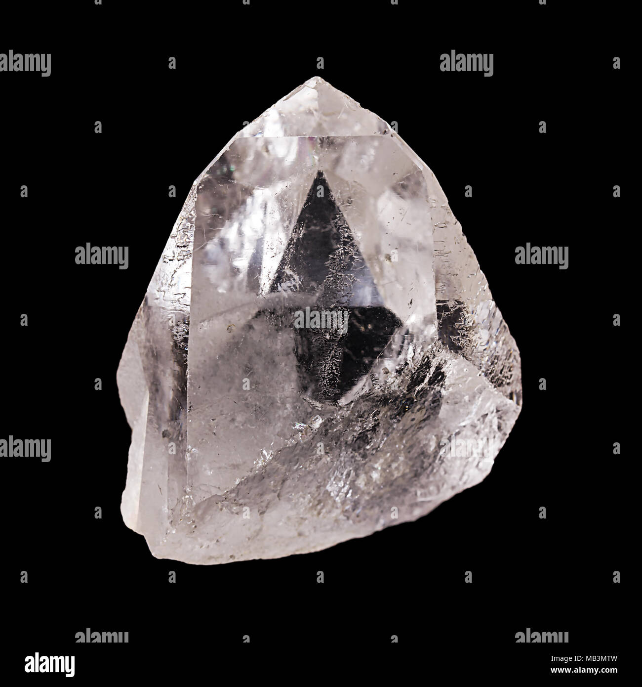 Rough quartz crystal on black background. With pyramid shaped optical illusion inside the mineral. Semi precious gemstone. Silica, silicon dioxide. Stock Photo