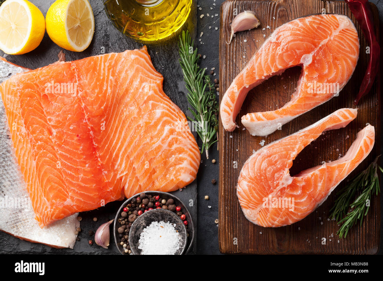 Raw salmon fish steaks and fillet with spices cooking on cutting board ...