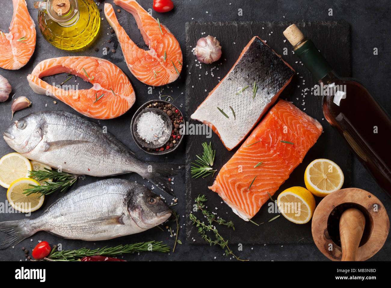 Raw salmon fish fillet and dorado with spices cooking on cutting board ...