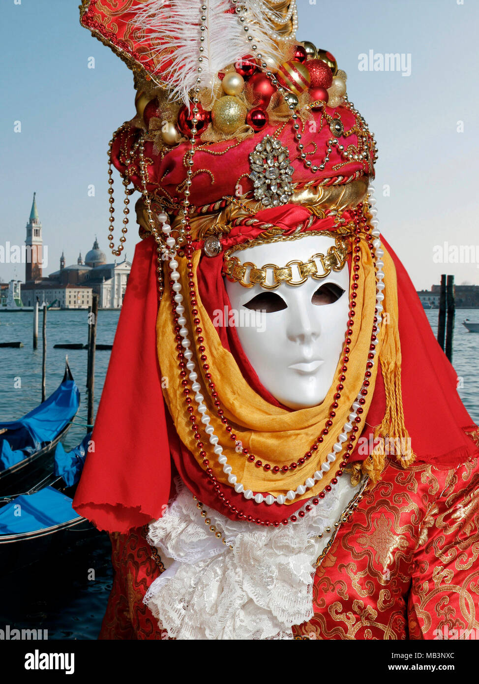 Person in mask at Carnival, gondolas dock, and San Giorgio Maggiore Church, Venice, Italy Stock Photo