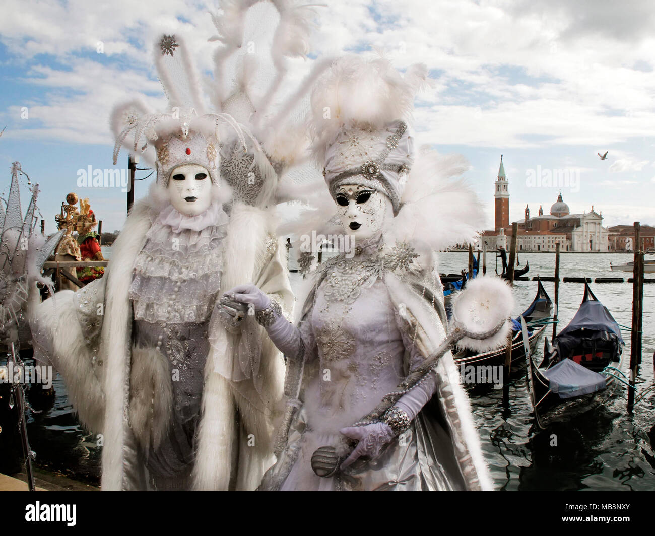 Couple in masks at Carnival, gondolas dock, and San Giorgio Maggiore Church in background, Venice, Italy Stock Photo