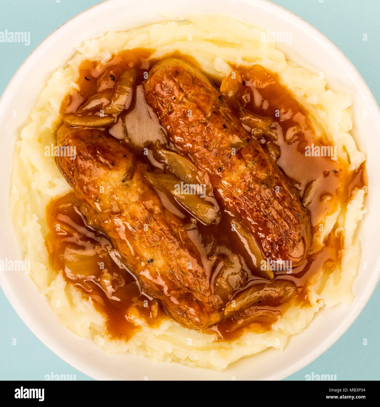 Sausage And Mashed Potatoes With Onion Gravy Against A Blue Background
