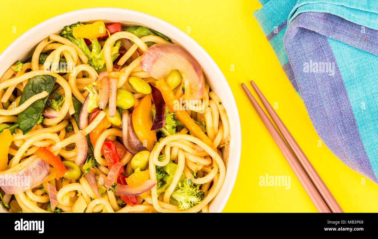 Stir Fried Egg Noodles With Fresh Vegetables Against A Yellow