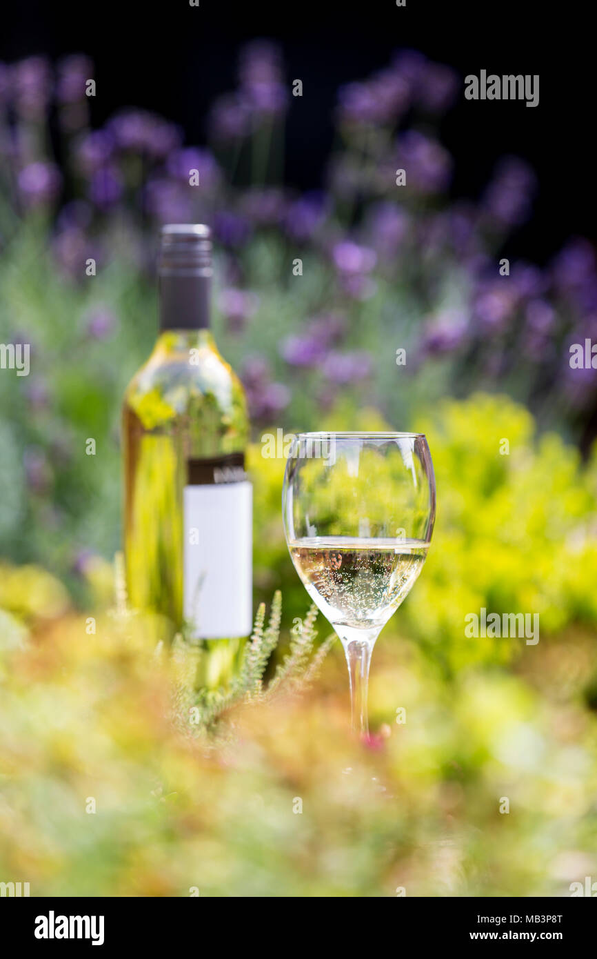 White wine in glass with bottle amongst flowers Stock Photo