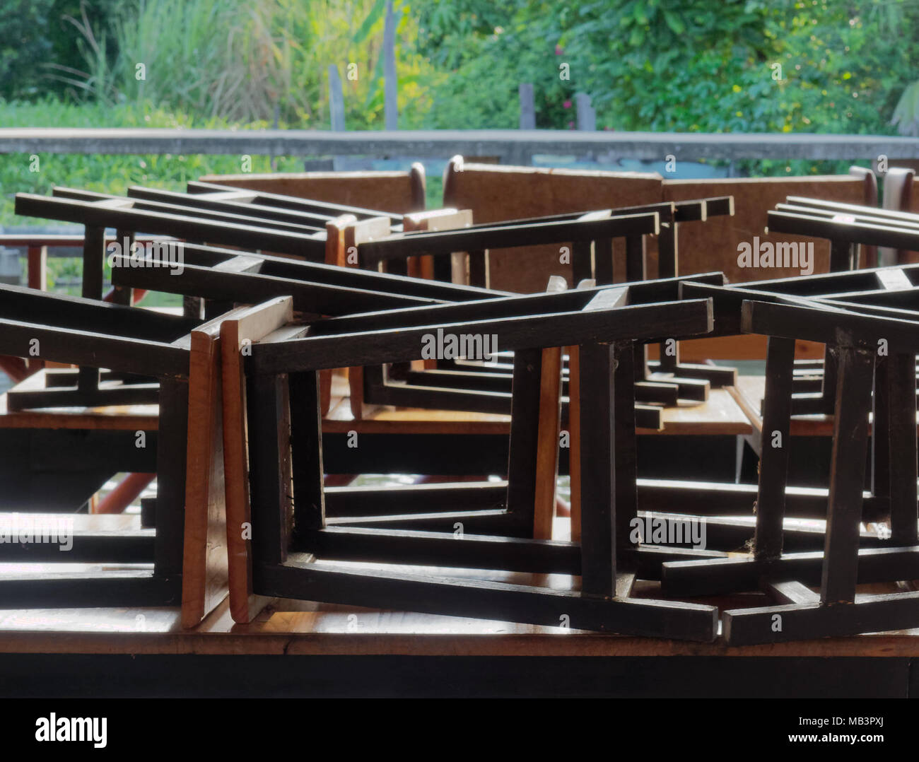Restaurant on raft by canal in countryside was closed with black wooden and metal chairs put on brown wooden tables Stock Photo