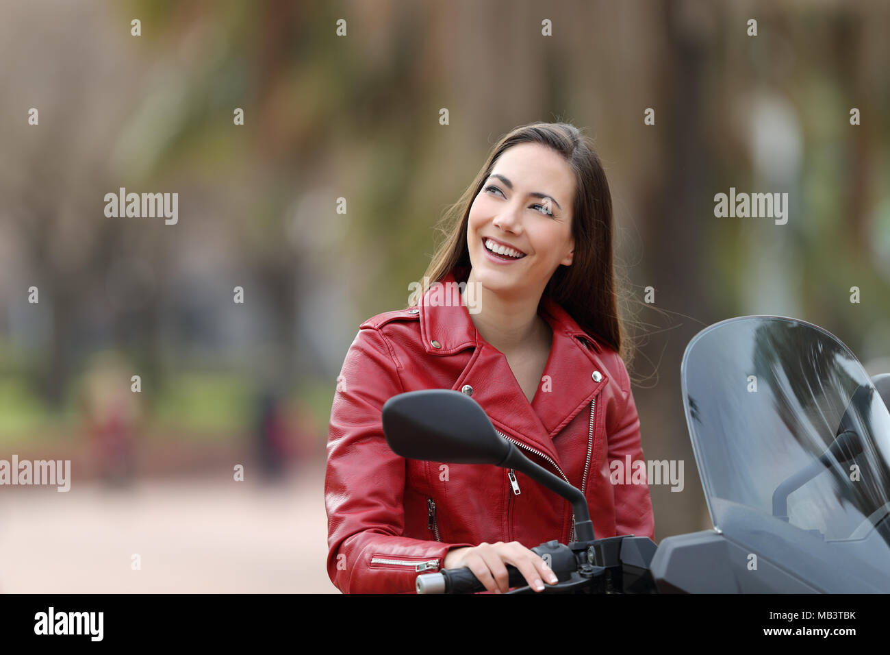 Biker thinking looking at side on her motorbike on the street Stock Photo
