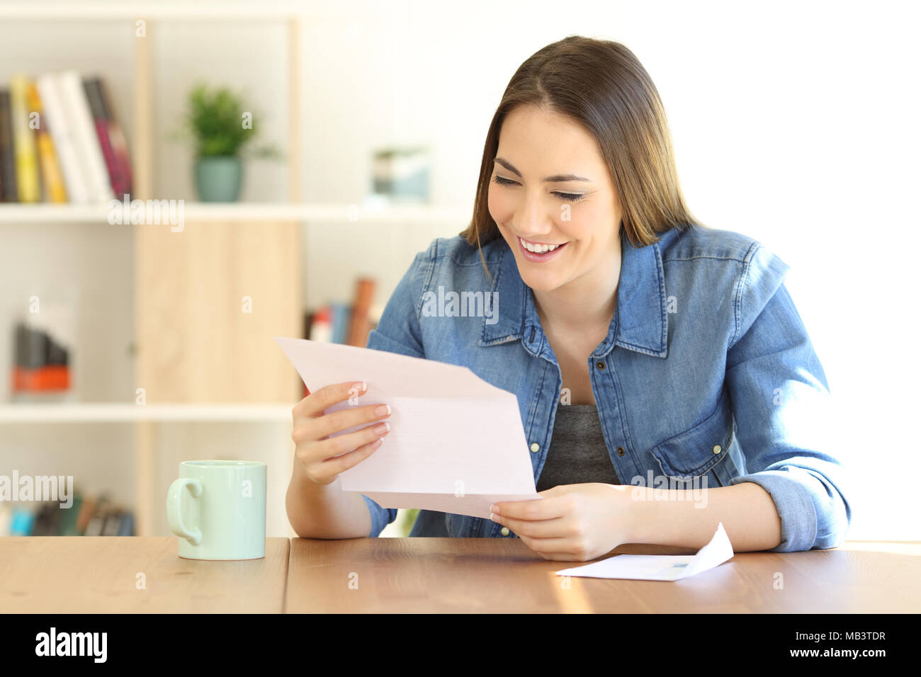 Happy woman reading a letter on a table at home Stock Photo