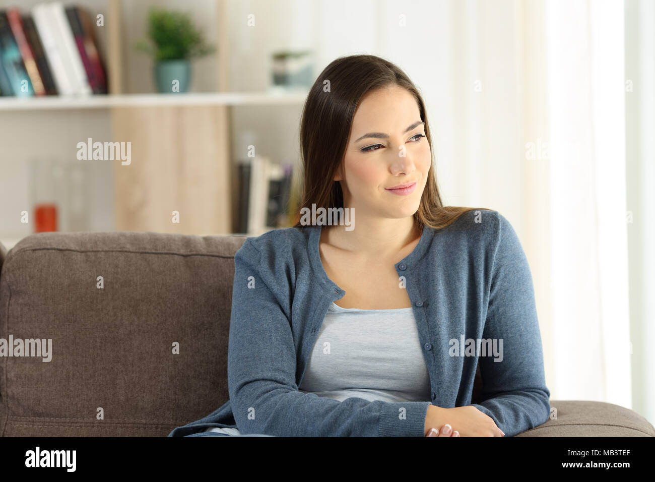 https://c8.alamy.com/comp/MB3TEF/distracted-lady-looking-outside-through-a-window-sitting-on-a-couch-in-the-living-room-at-home-MB3TEF.jpg