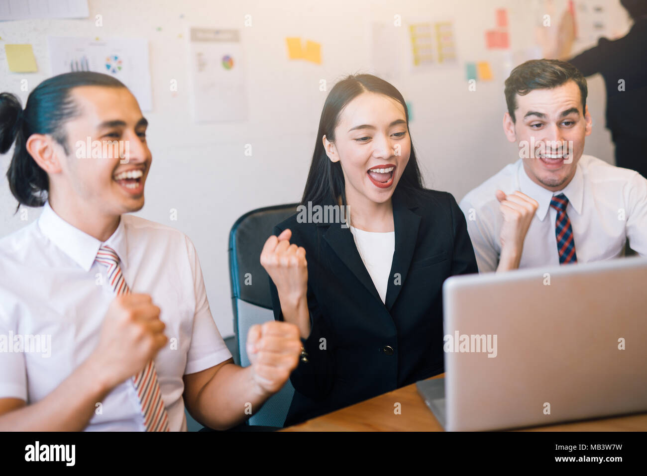 Happy business people celebrate success looking at laptop screen in the ...