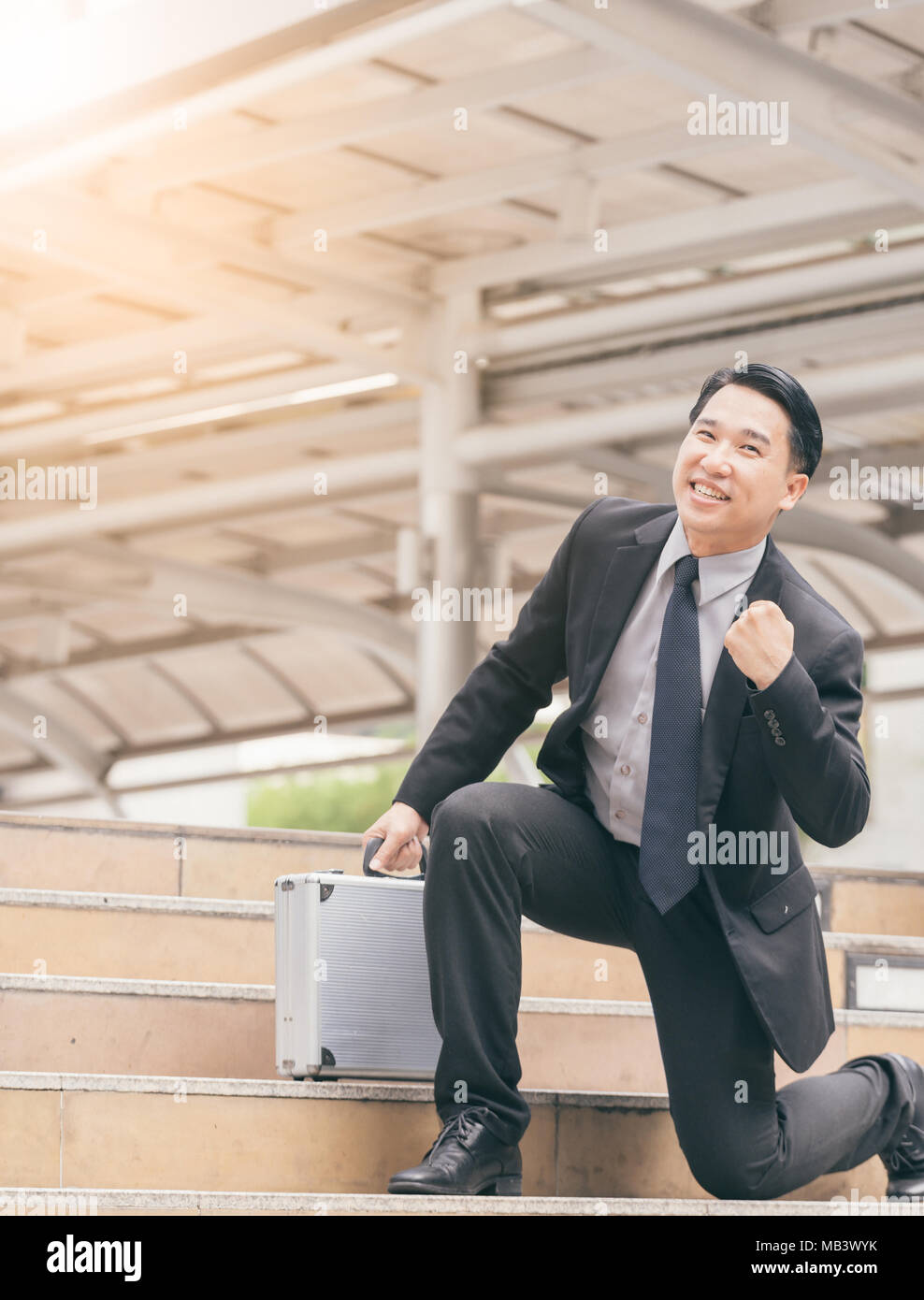 Businessman smiling and raising his fist in the air, with office ...