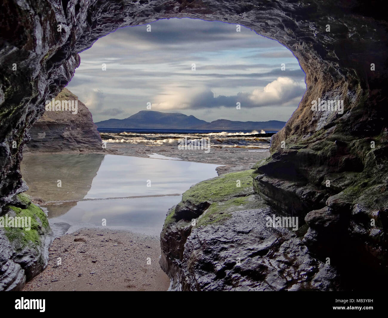 Cave at Thruppeny Pool, Bundoran, with the Donegal hills on the horizon Stock Photo