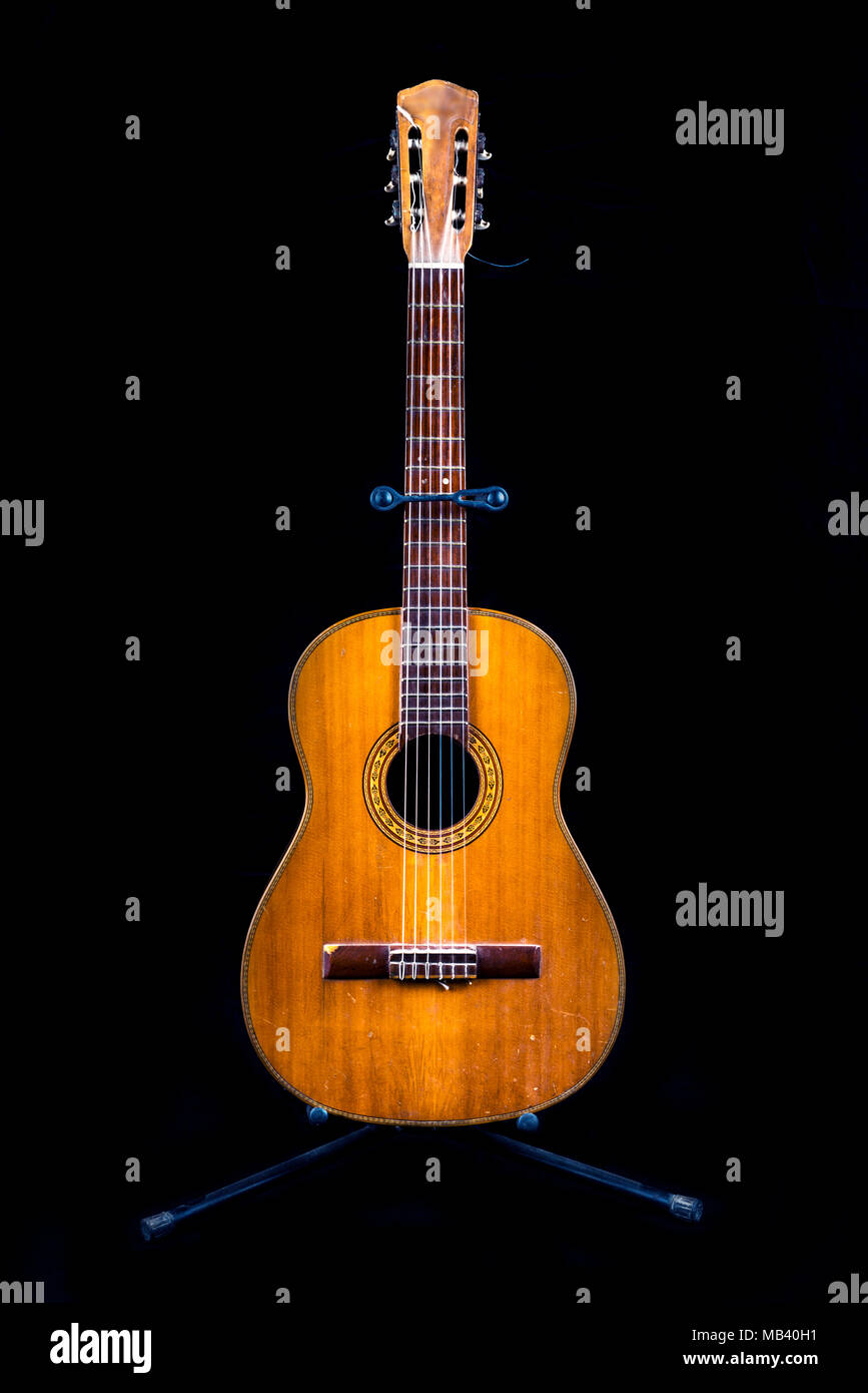 very old guitar on a stand isolated on black background Stock Photo