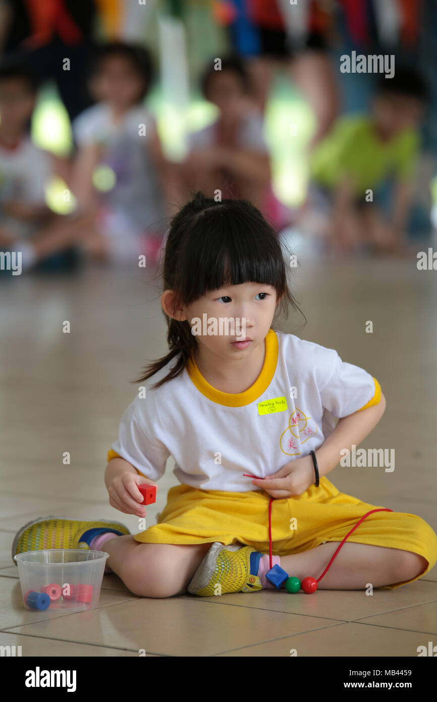 Children are in the game of threading the beads during their kindergarten sport day. Stock Photo