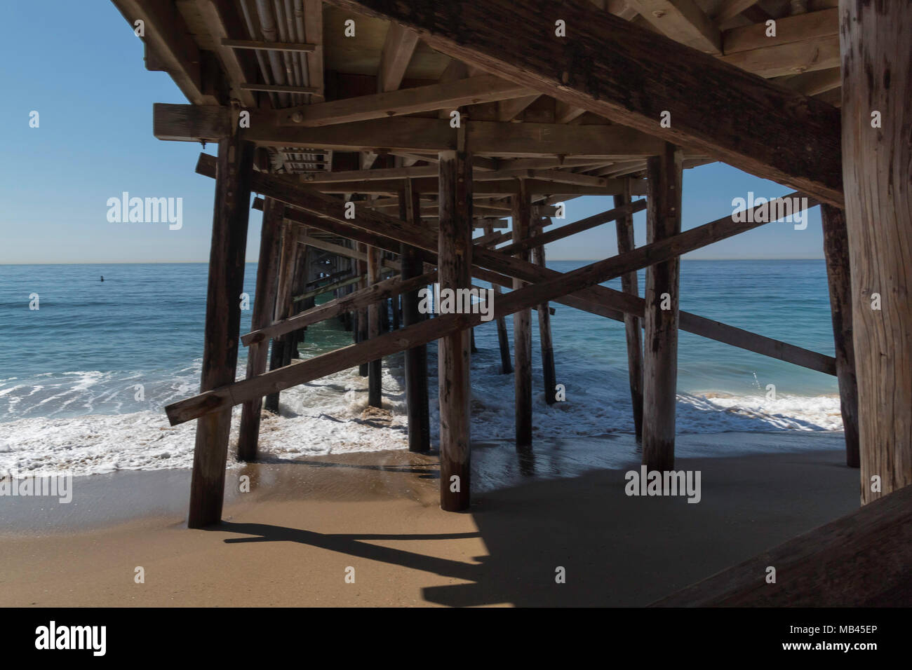 Under the Wooden Pier, wooden structure details, blue ocean waters, Pacific, sand, sunny, misty, daylight, summer, holidays, Newport Beach, California Stock Photo