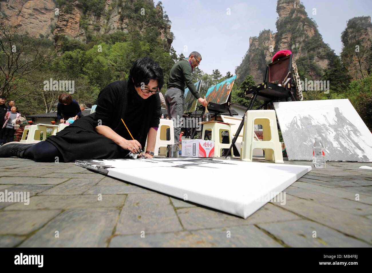 Zhangjiajie, China's Hunan Province. 6th Apr, 2018. Giovanna Fezzi (L) from Italy paints at Zhangjiajie UNESCO Global Geopark at Wulingyuan District of Zhangjiajie City, central China's Hunan Province, April 6, 2018. About 21 artists coming from Italy took part in a cultural event at the geopark which is known for its quartzose sandstone landform. This geopark is one of the geoparks in China that have already been chosen by UNESCO on its World Network of Geoparks. Credit: Wu Yongbing/Xinhua/Alamy Live News Stock Photo