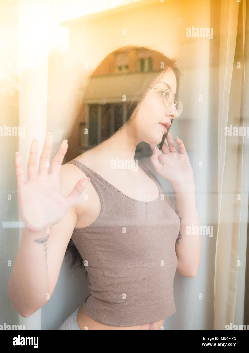 Pretty teenage girl behind window hands up looking up out of concept of thinking ahead about future Stock Photo