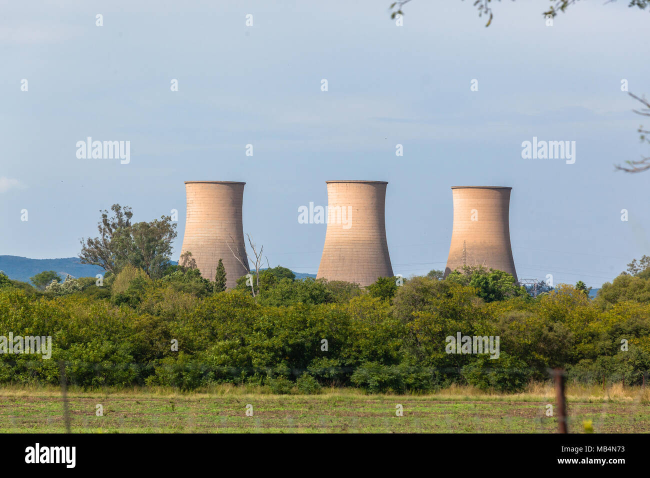 Three power station water cooling towers building structures outside city in countryside. Stock Photo