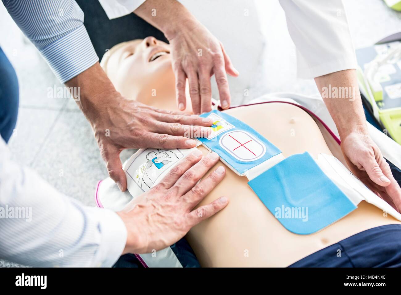 First-aider placing automated external defibrillator (AED) pads on a CPR training dummy. Stock Photo