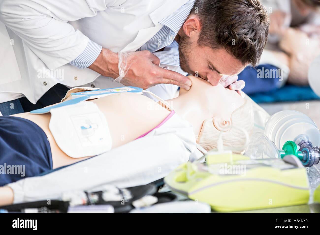 Doctor practising rescue breaths on a CPR training dummy. Stock Photo