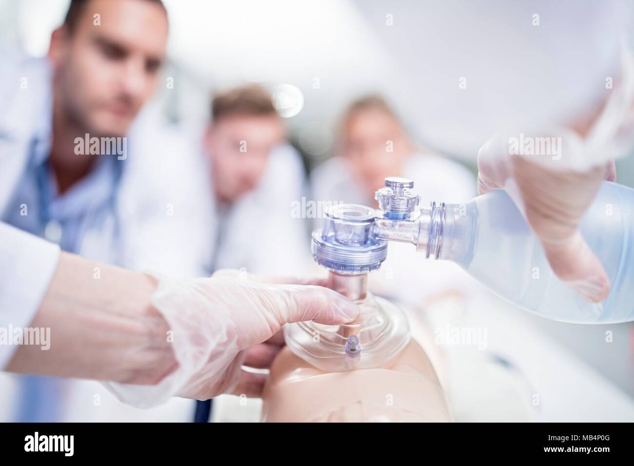 MODEL RELEASED. Doctor practising bag-valve-mask ventilation on a training dummy. Stock Photo