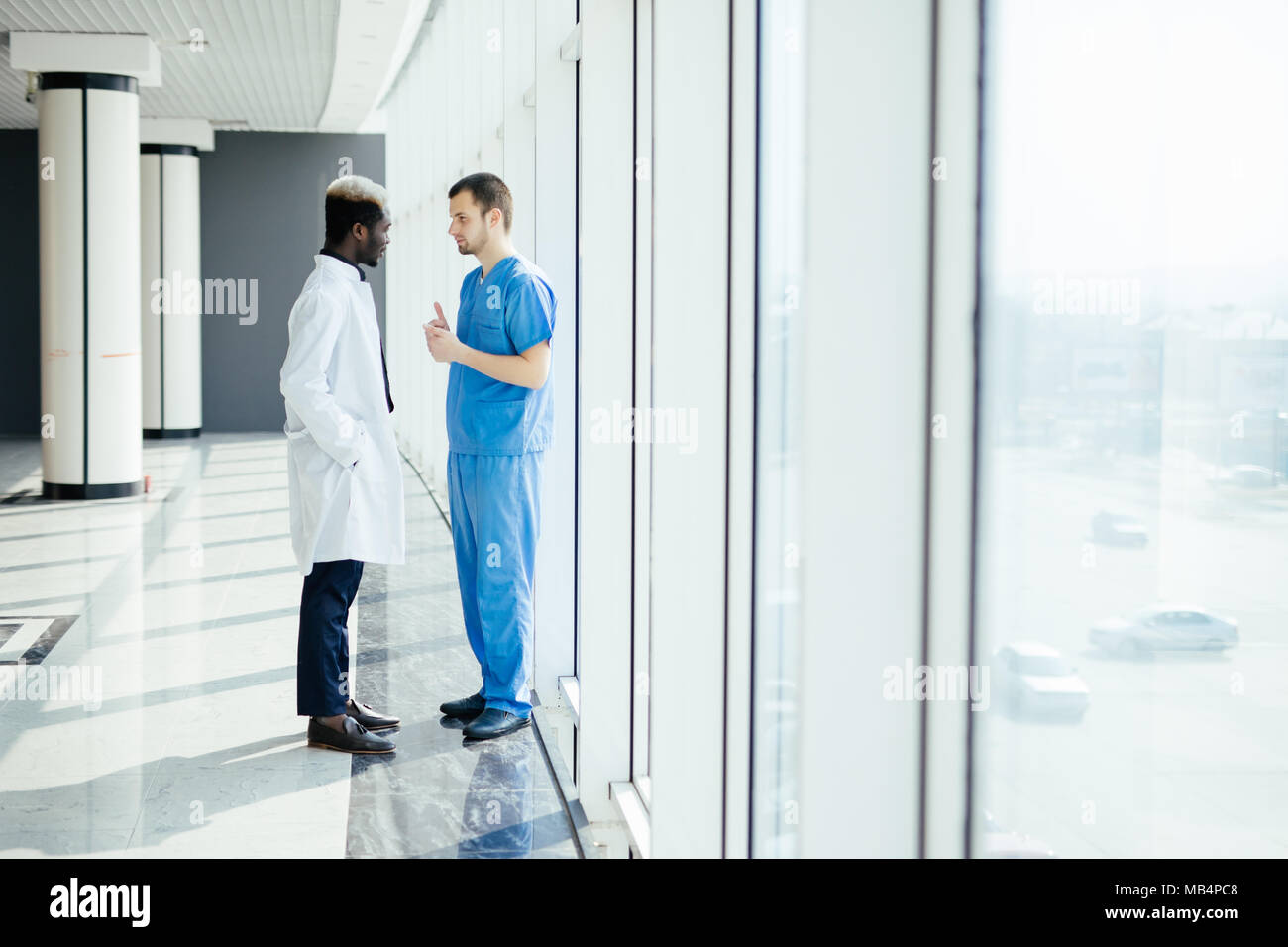 Two doctors discussing diagnosis while walking in hospital Stock Photo