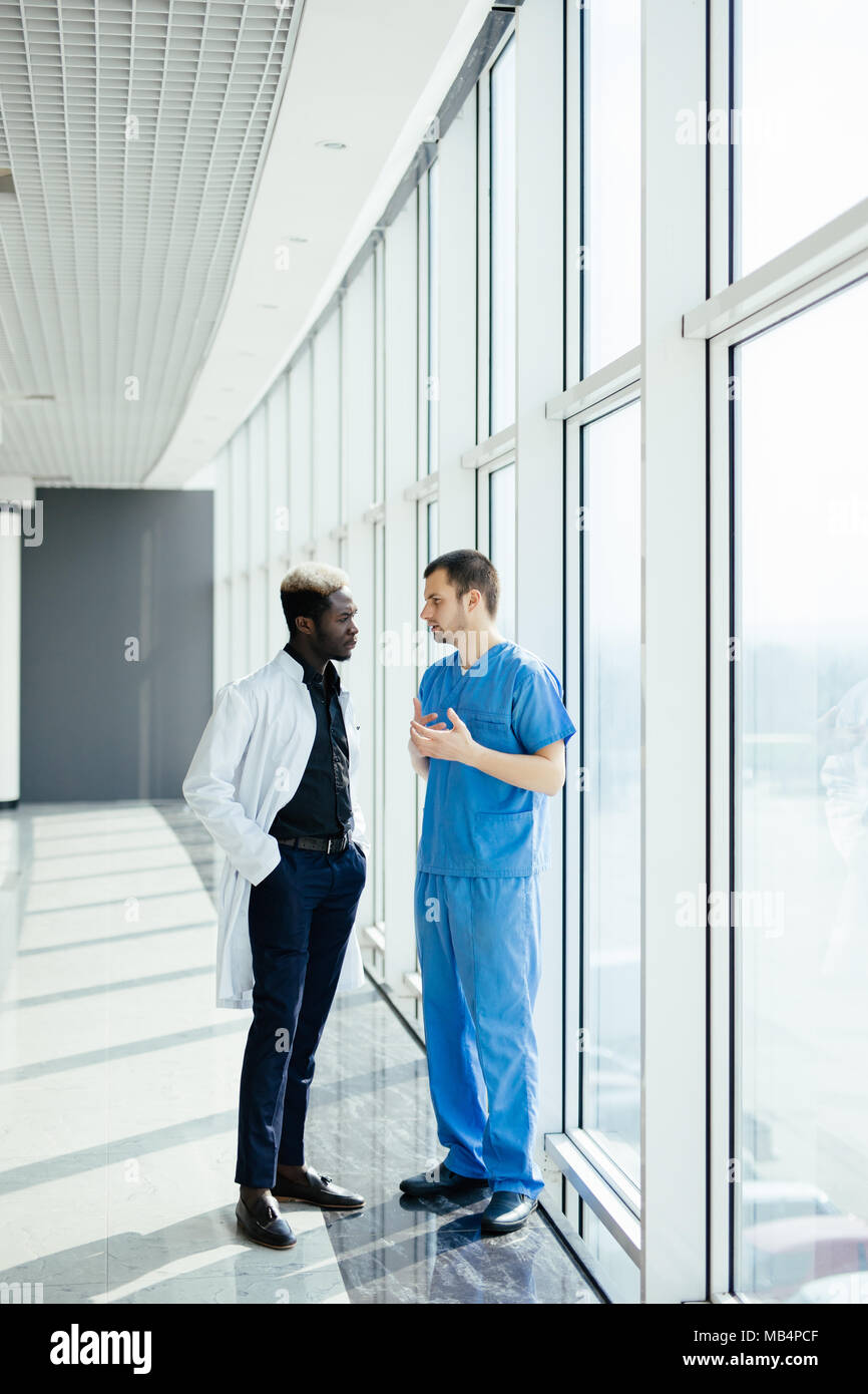 Two doctors discussing diagnosis while walking in hospital Stock Photo