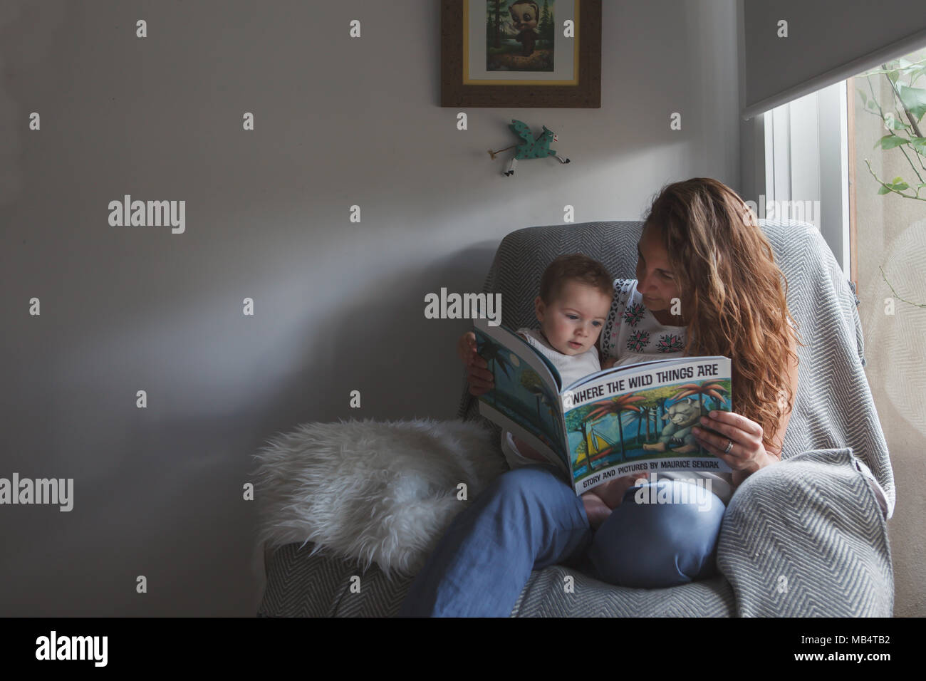 Mother reading book to baby boy in an arm chair Stock Photo
