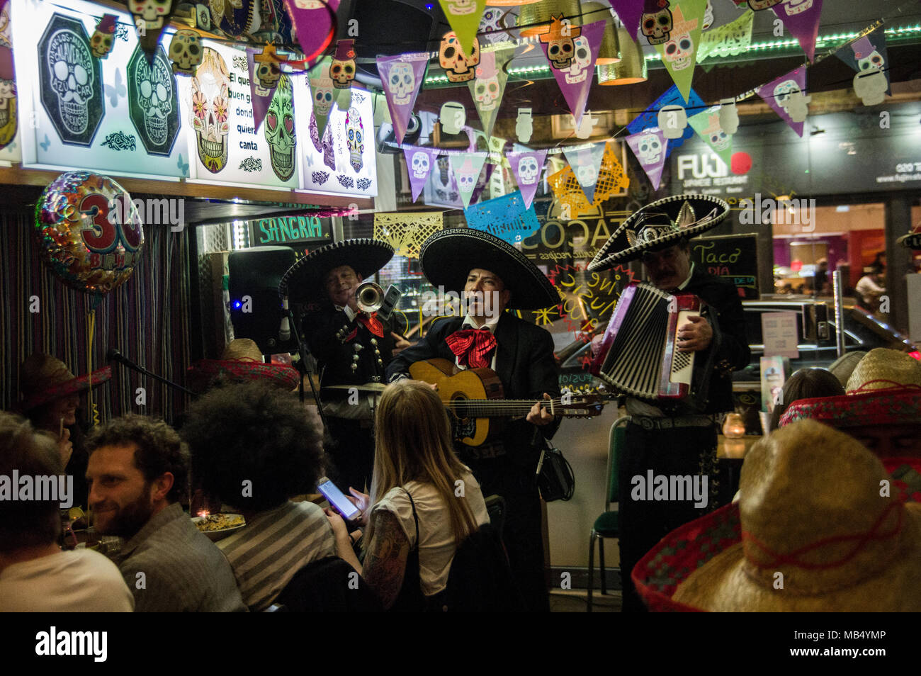 Mariachi players in traditional sombrero hats serenading diners in a