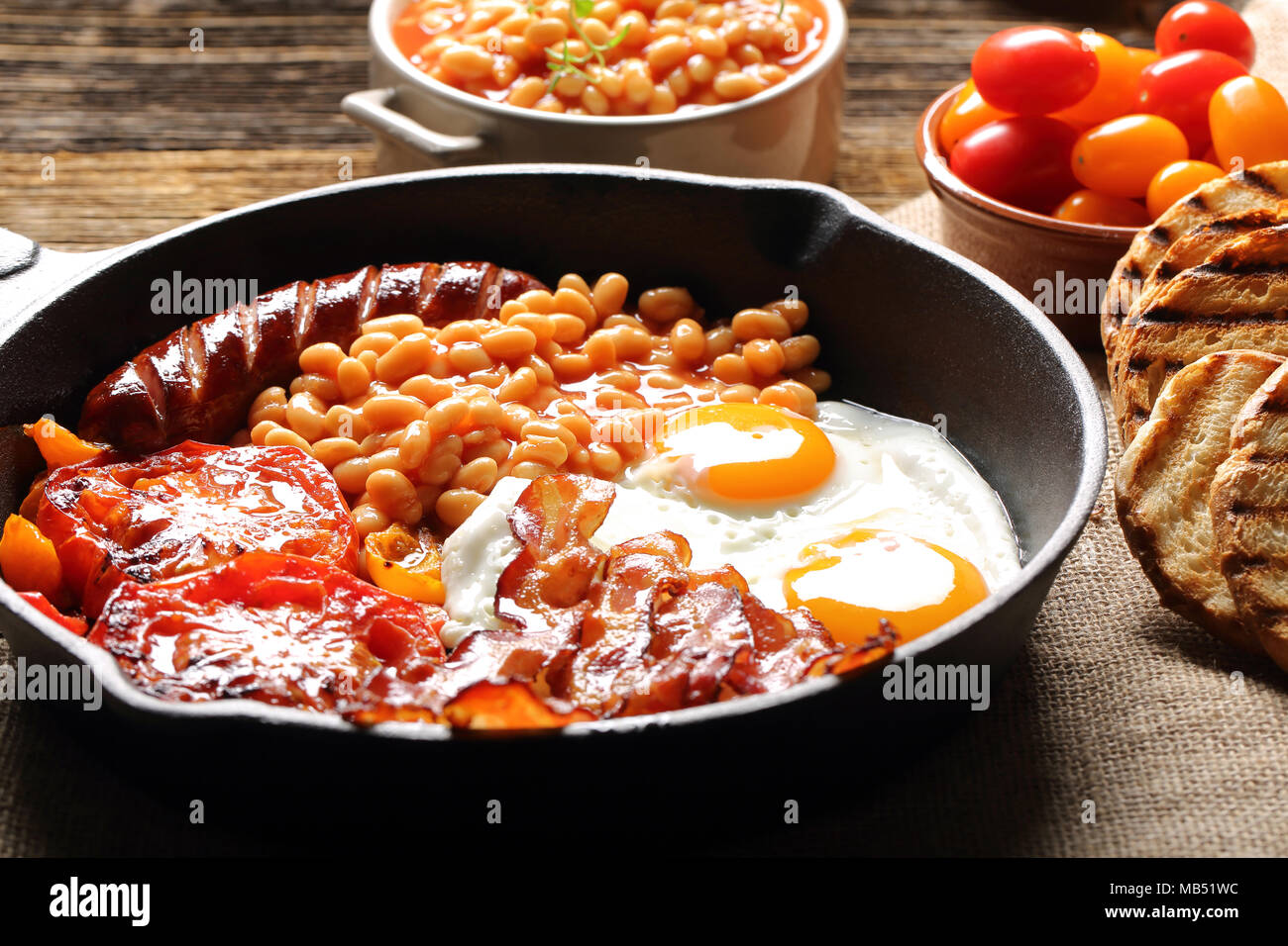 English Breakfast with sausages, grilled tomatoes, egg, bacon, beans