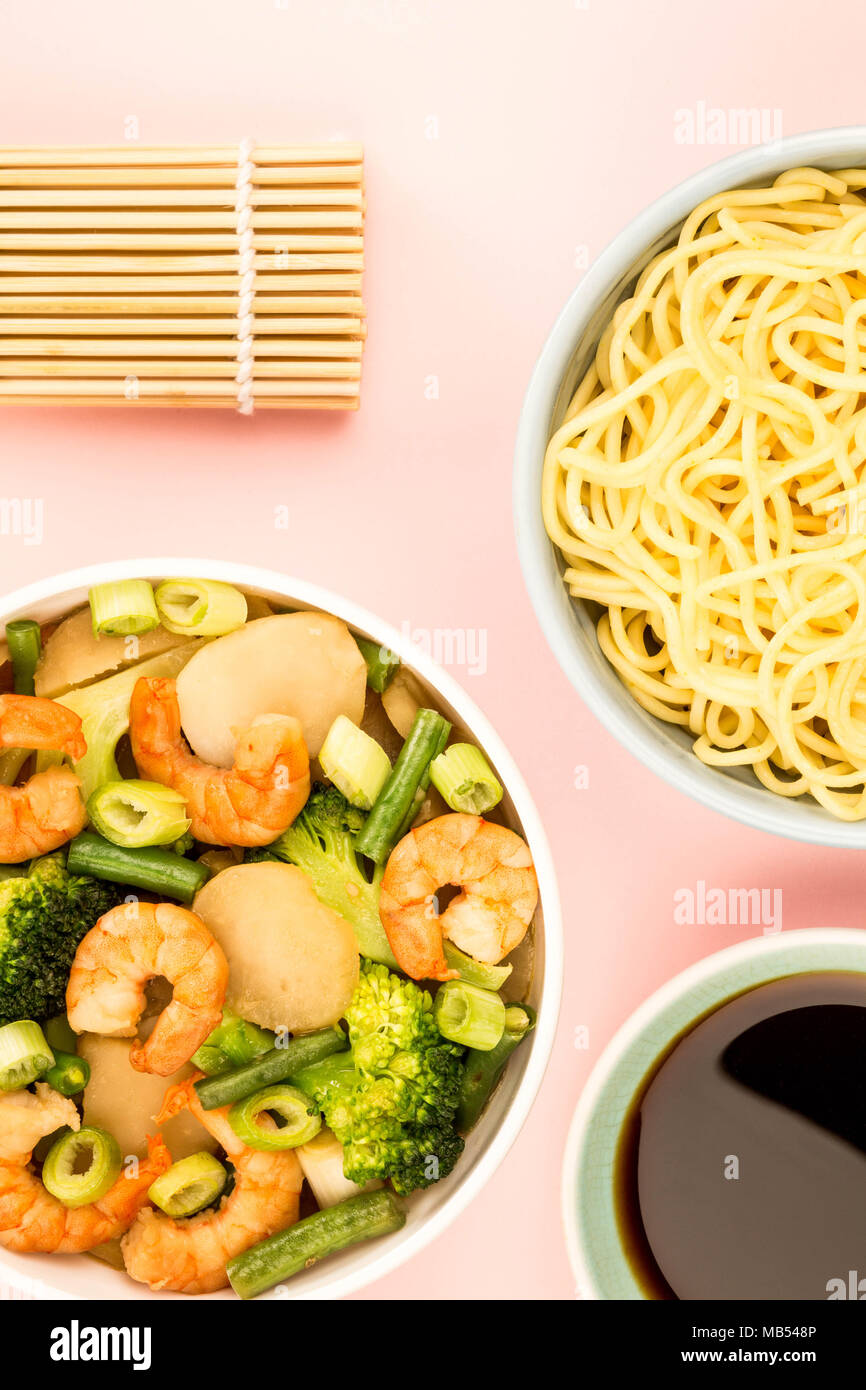 Chinese Style King Prawn With Ginger Broccoli And Spring Onions Against A Pink Background Stock