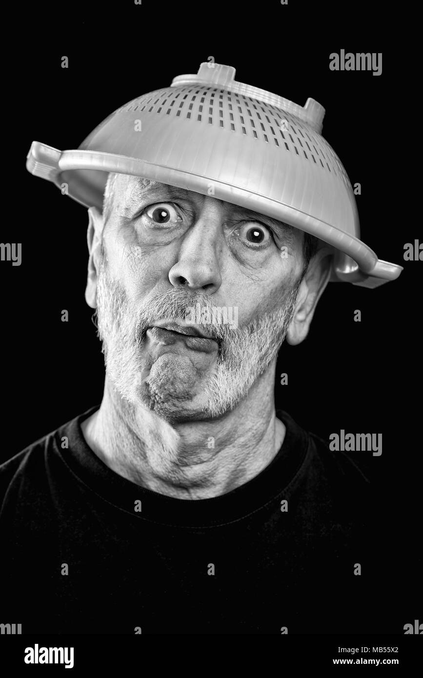 Dramatic black and white Portrait of a mad man with a plastic strainer on the head Stock Photo