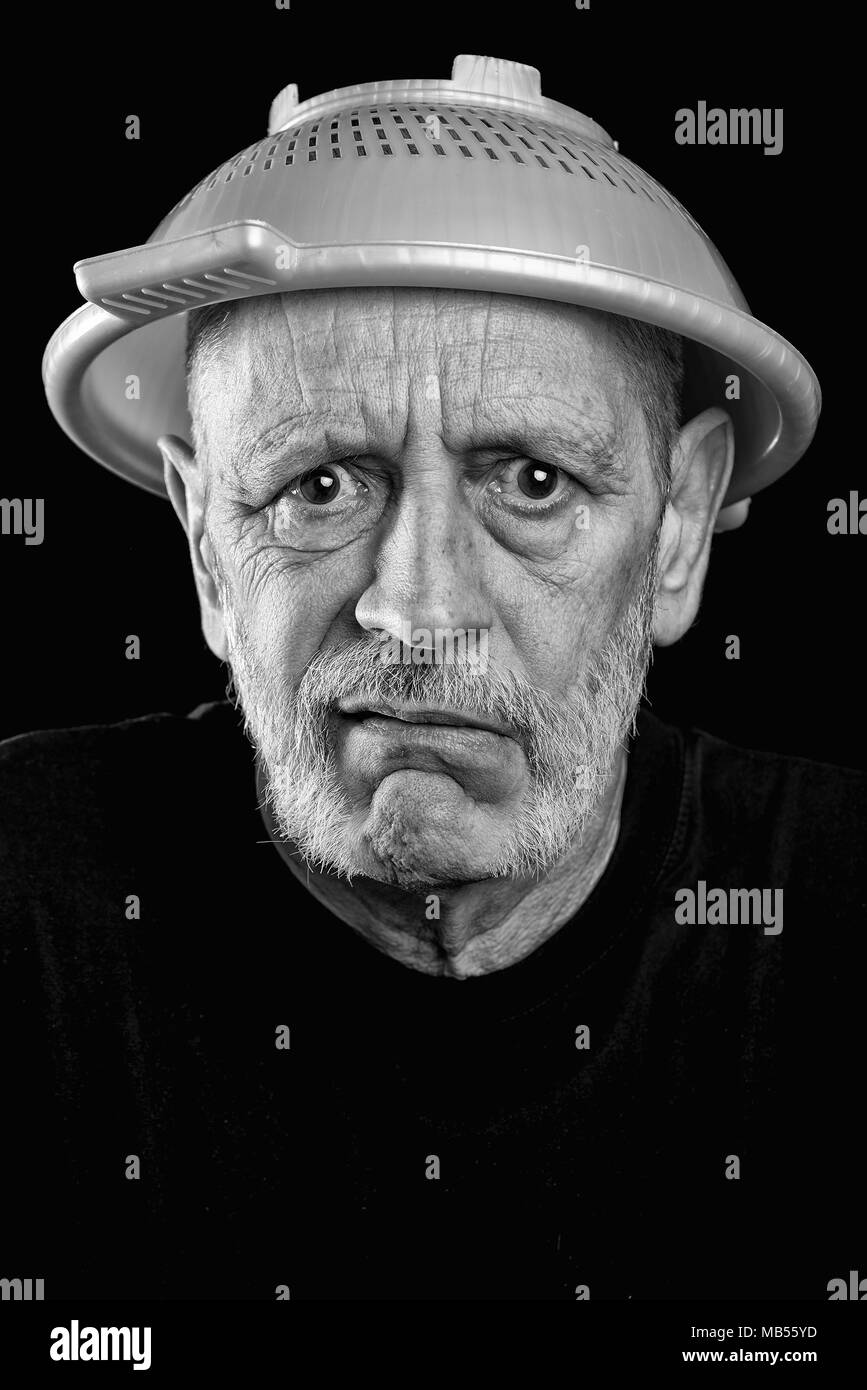 Dramatic black and white Portrait of a mad man with a plastic strainer on the head Stock Photo