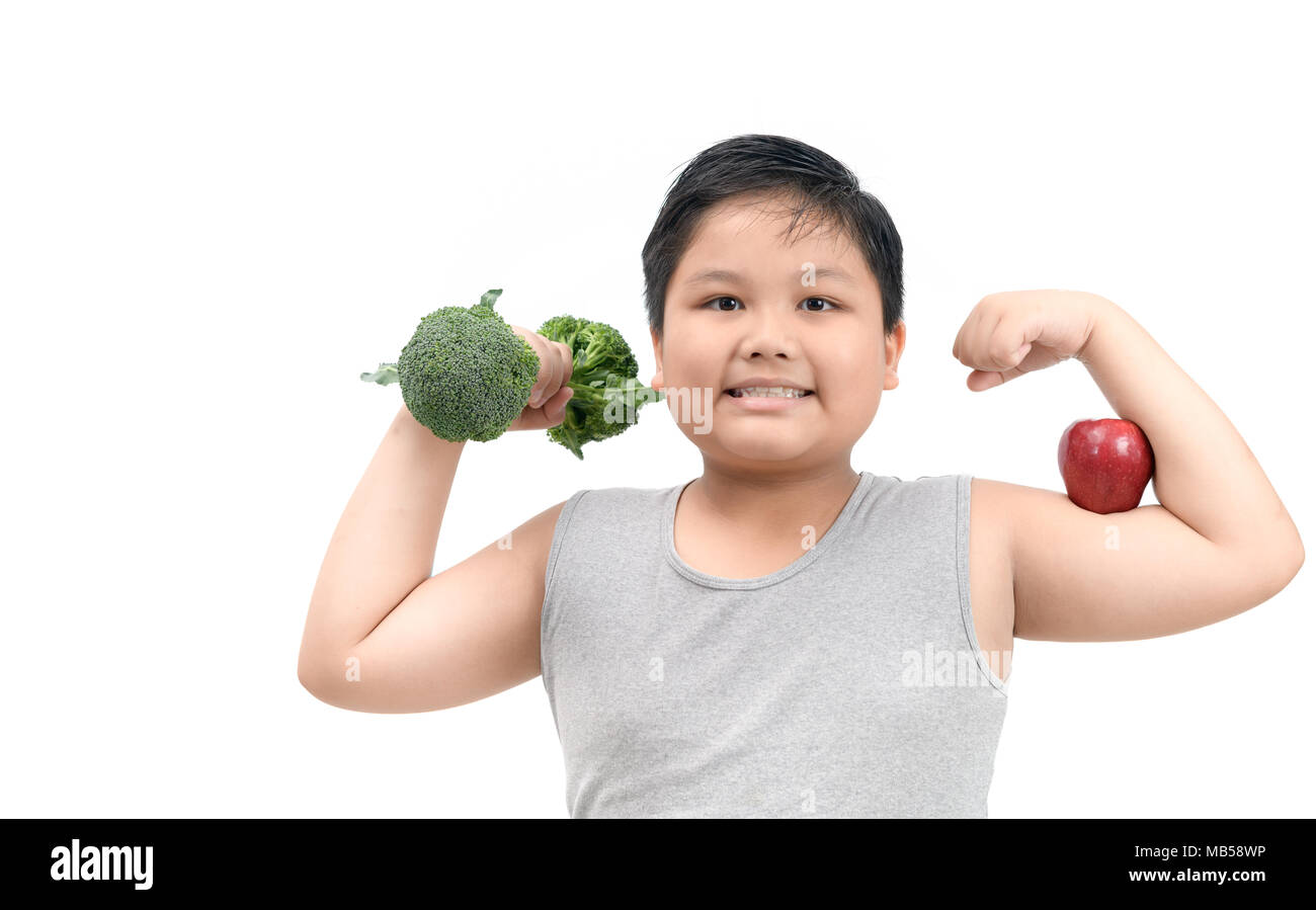 Obese fat boy holding a broccoli dumbbell and show muscle with apple isolated on white background, diet and exercise for good health concept Stock Photo