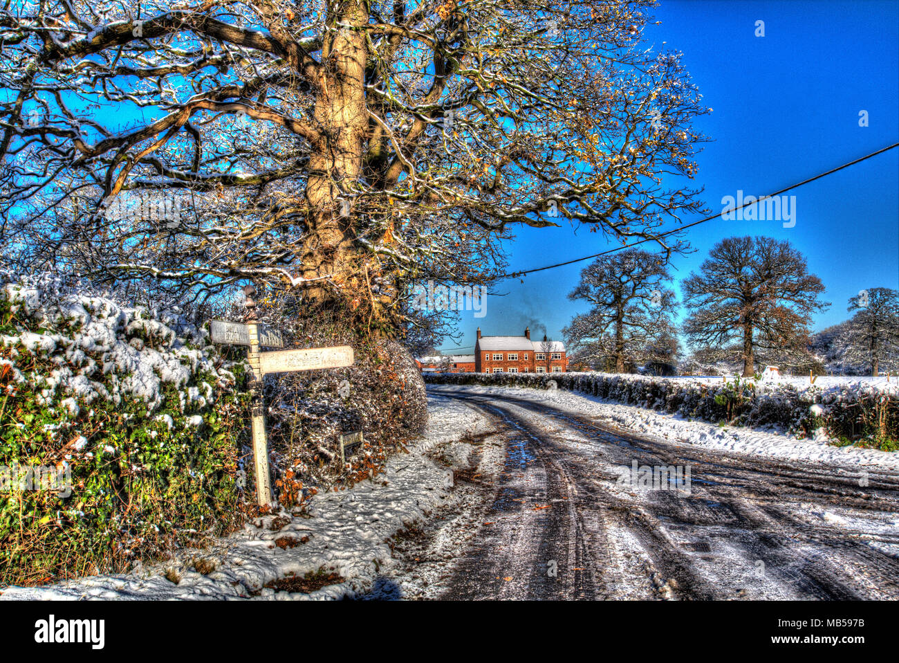 Village of Coddington, England. Artistic view of a rural snow covered pre Worboys direction sign, in rural Cheshire. Stock Photo