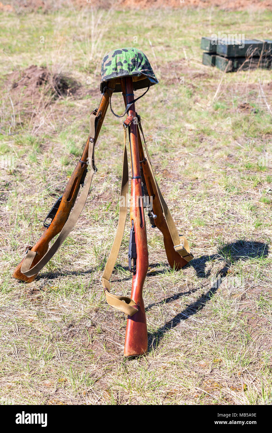 Vintage Russian military rifles (Mosin system, model of 1938) and German helmet at the battle field Stock Photo