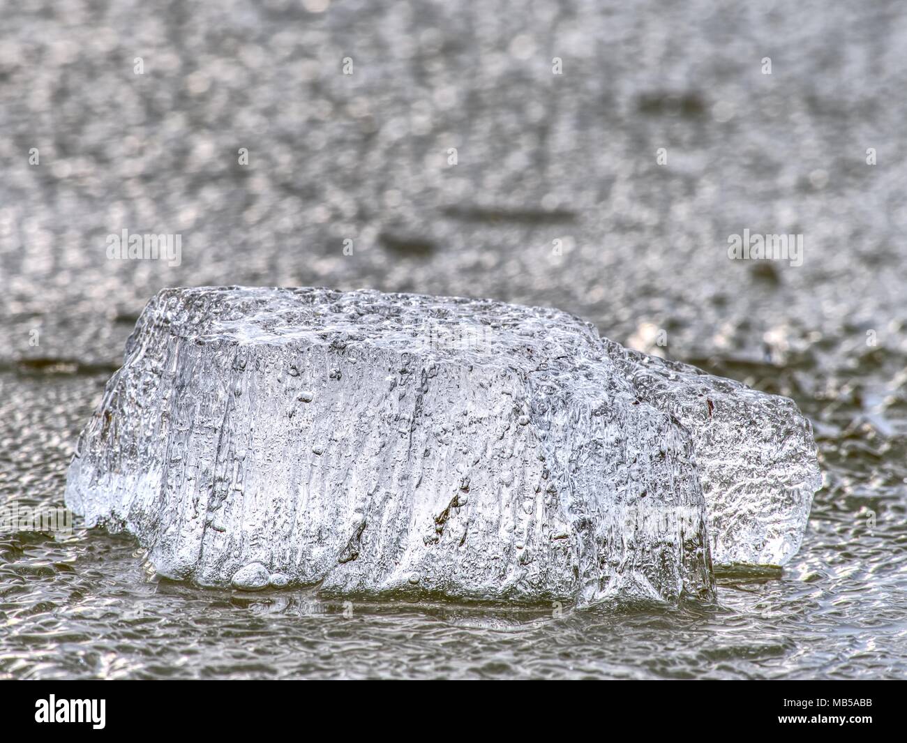 Detail of melting ice block floating in the river. Frozen river surface