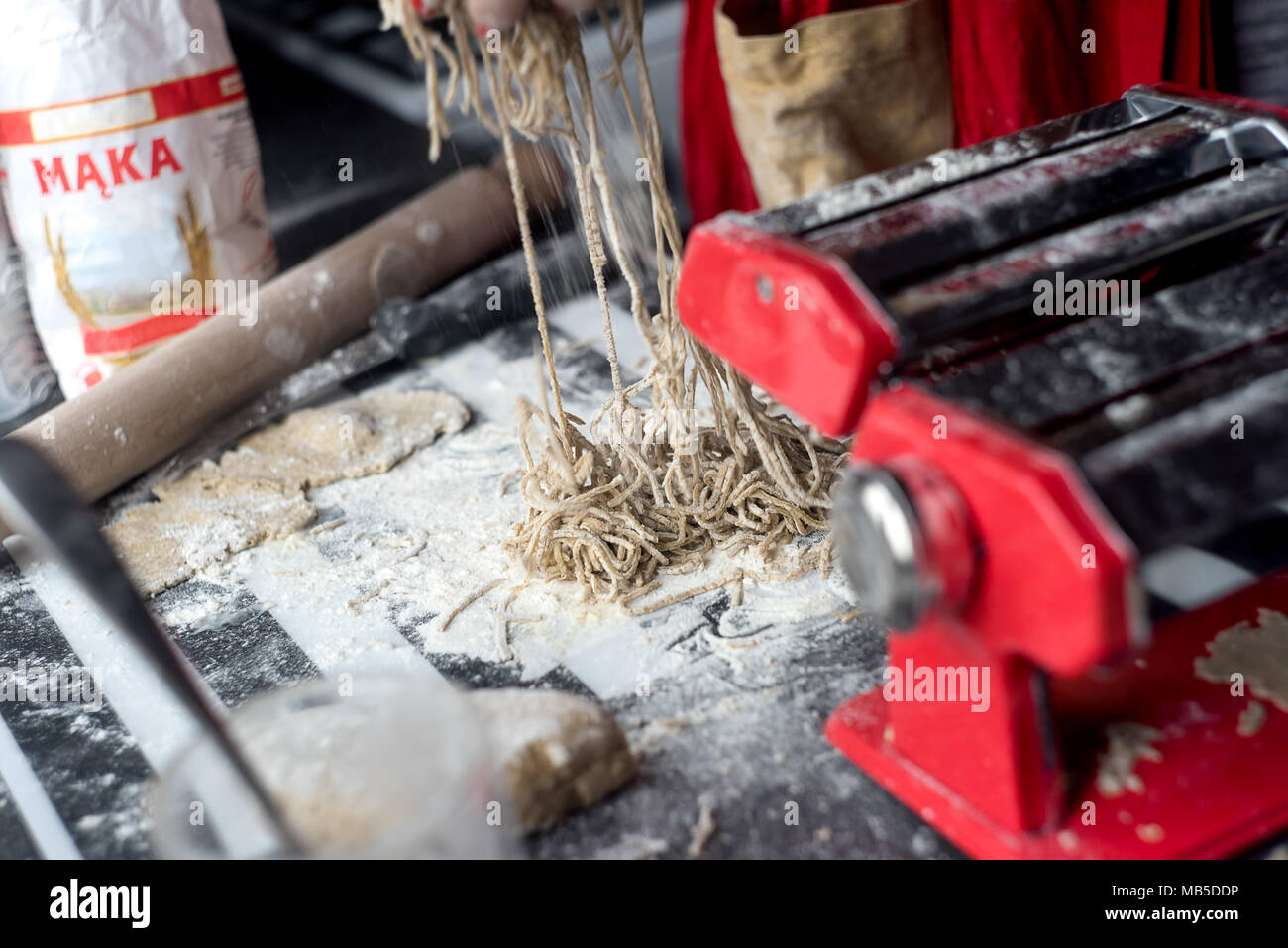 Woman preparing pasta, using red pasta grinder. Stock Photo