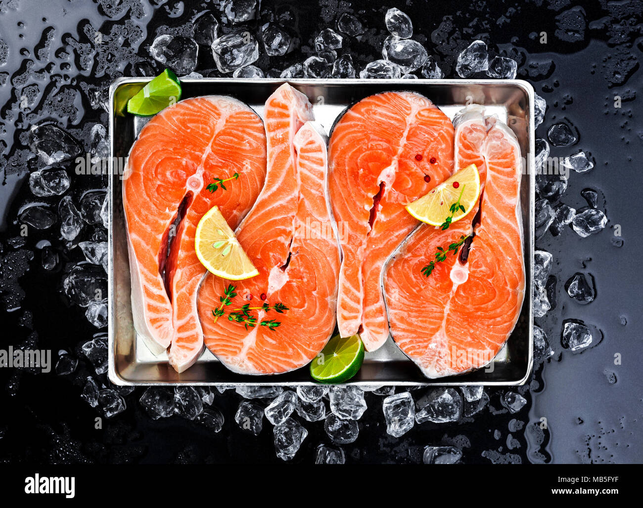 Salmon steaks on ice on black background Stock Photo - Alamy