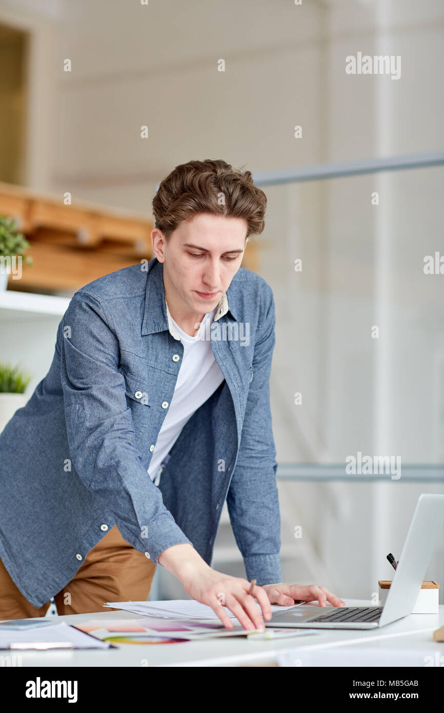Serious designer working with patterns and using his laptop at office Stock Photo