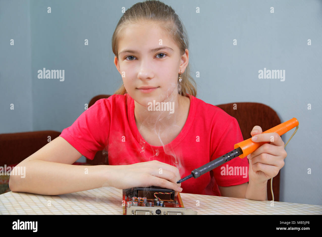 The teenager is learning to solder. Repair of a computer graphics card Stock Photo