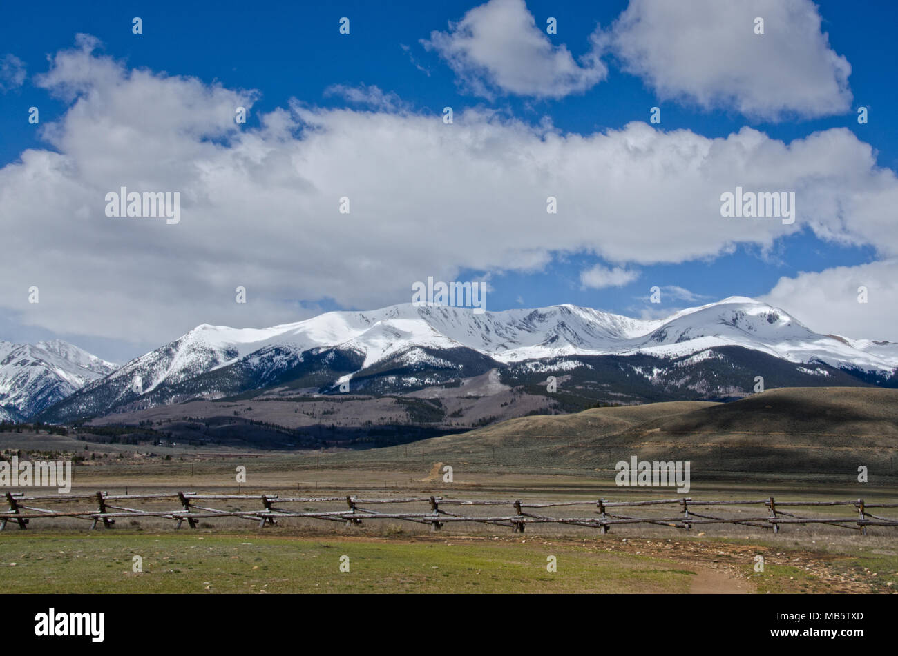 Mount Massive, the second tallest peak in Colorado, is covered in spring snow with a log fence in the foreground. Stock Photo