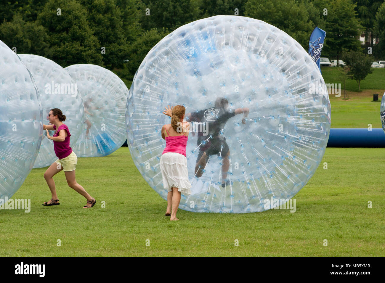 Women push young people around in rolling zorbs at the 3rd Annual Atlanta Ice Cream Festival at Piedmont Park, on July 27, 2013 in Atlanta, GA. Stock Photo