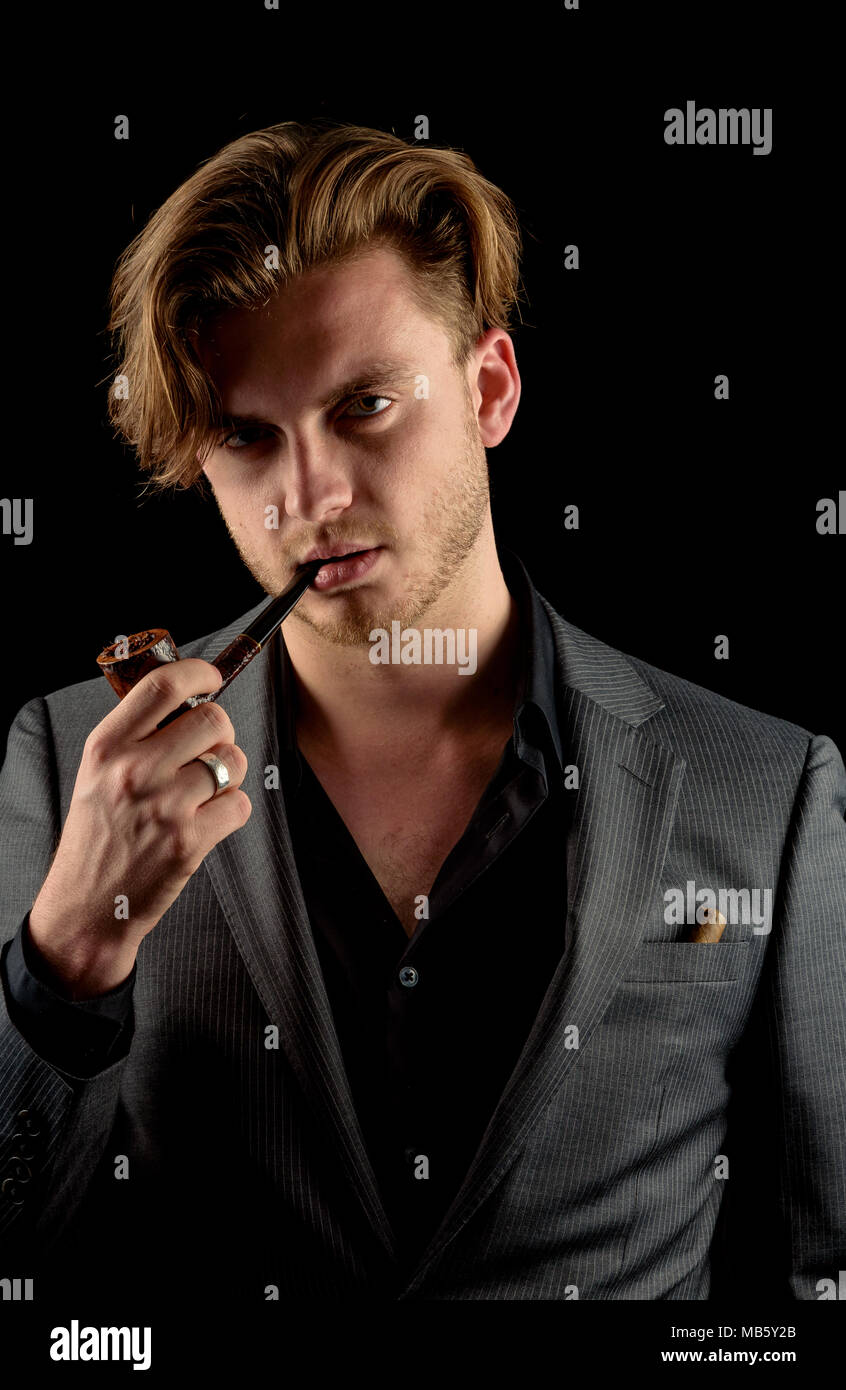Caucasian male model in a charcoal suit with a wooden pipe Stock Photo