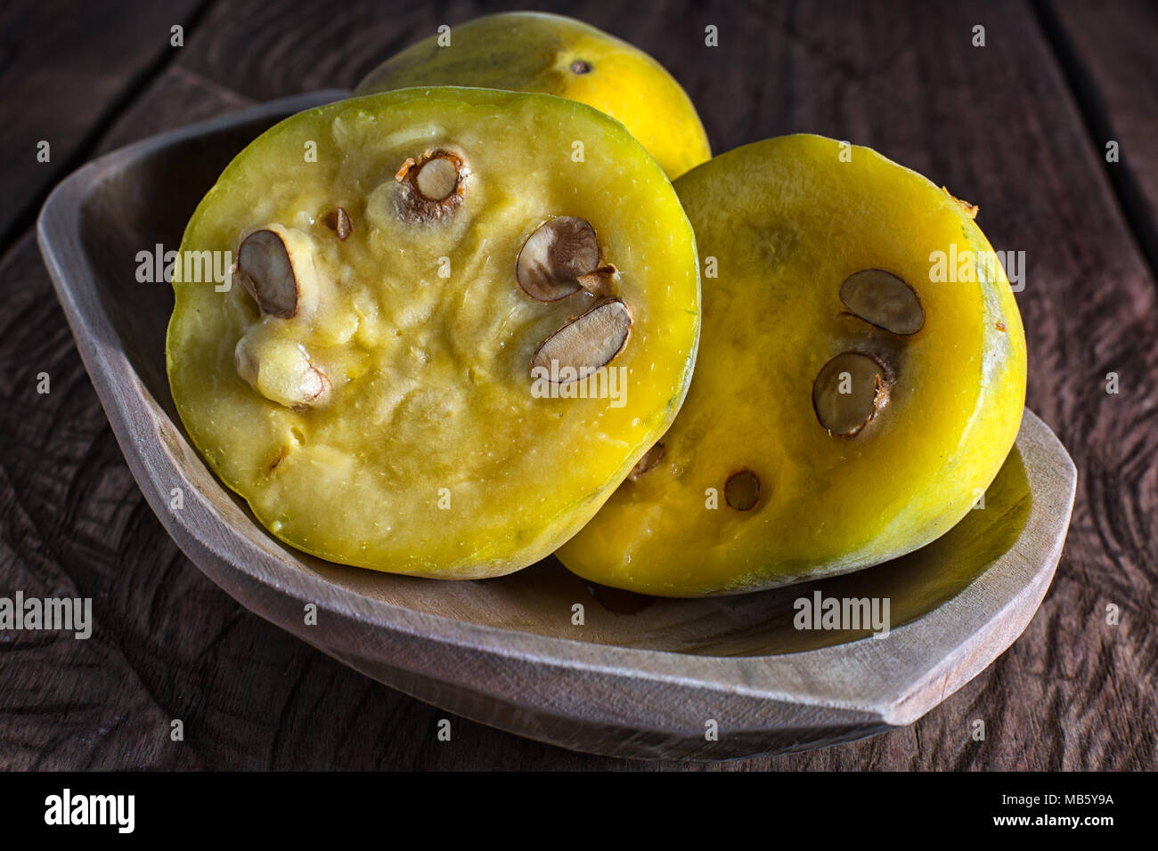 cut half rare araza fruits in a wooden bowl on rustic background Stock Photo